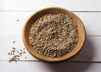 Seeds of rye for germination in a wooden bowl on a white background