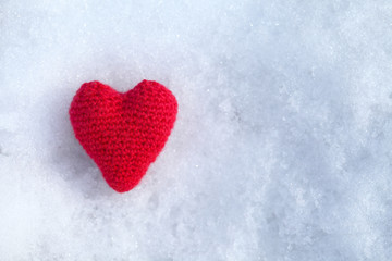 The heart is tied with red woolen threads and lies on white snow. Template for a greeting card for the feast of Saint Valenotine.