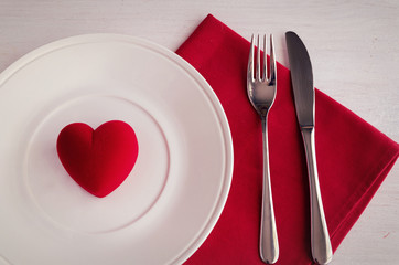 Fototapeta na wymiar St Valentines Day place setting, plate, cutlery, line napkin and decorative heart on white background. Love romantic dinner concept.
