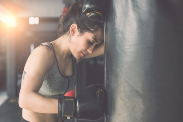 Asian young woman doing exercise with Thai boxing (Muay Thai) equipment in gym. Health and fitness...