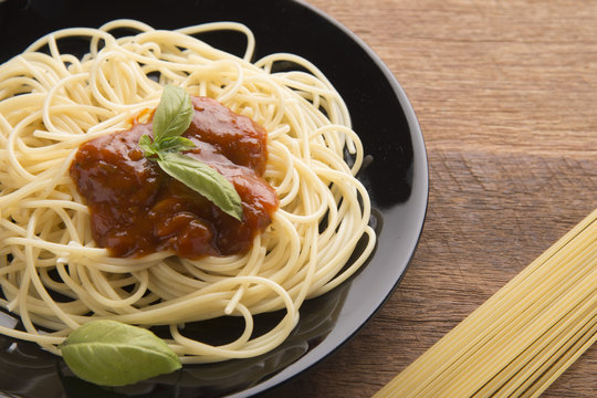 Spaghetti bolognese in black plate on wooden table background,Spaghetti with Spicy Mixed sauce and meat