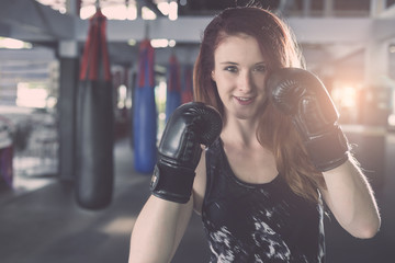 Young caucasian woman doing exercise with Thai boxing (Muay Thai) equipment in gym. Health and...