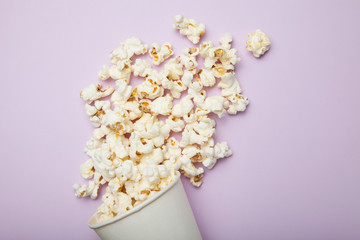 Popcorn in white bucket on pink background.