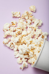 White popcorn and paper package isolated on pink background.