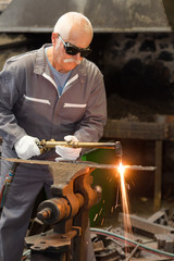 senior blacksmith using blowtorch