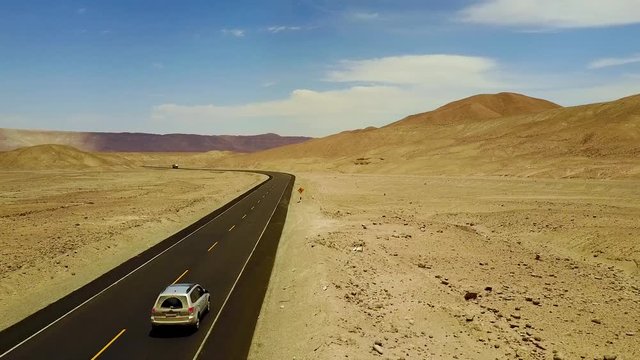 Drone shot flying close to an SUV traveling through the Atacama desert