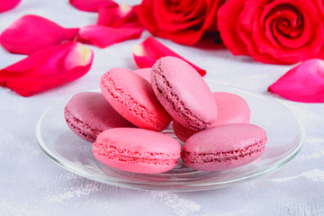 Pink and purple macaroons on a gray table surrounded by pink and white flowers.