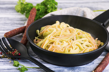 Color spaghetti in a frying pan and seasoning on a wooden table