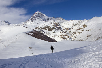 Snow-covered peak of Mount Kazbek, footpath, winter landscape. View from the Holy Trinity Church, Gergeti, Georgia