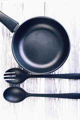 clean frying pan and a fork with a spoon on a wooden board
