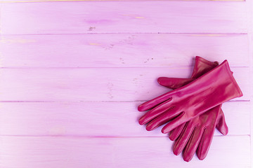 Leather red gloves on a pink wooden background