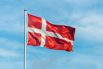Naklejka premium Danish flag waggling in the wind with sky in background