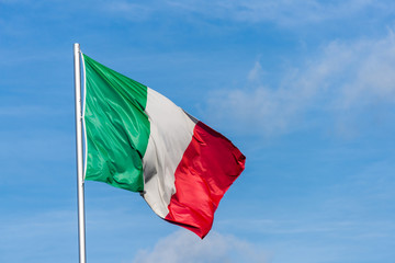 Fototapeta na wymiar Italian flag waggling in the wind with sky in background