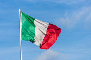 Italian flag waggling in the wind with sky in background