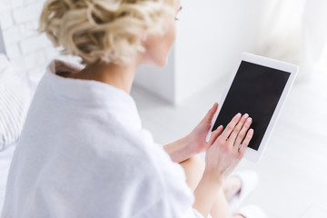 cropped shot of woman in bathrobe using digital tablet with blank screen