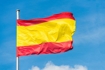 Spanish flag waggling in the wind with sky in background