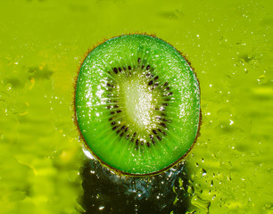 A cross-sectional view of juicy kiwi on a green background