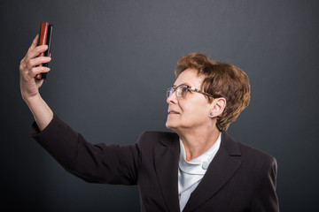 Side view of business senior lady taking selfie