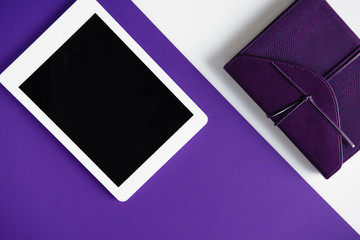 top view of tablet and notebook on white and purple surface