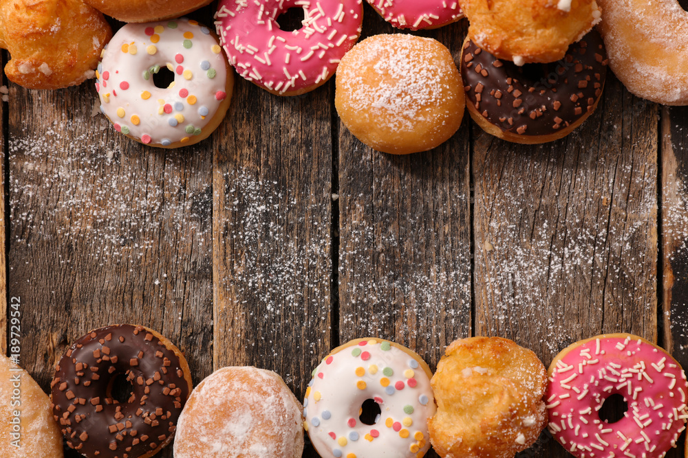 Poster assorted donuts on wood background