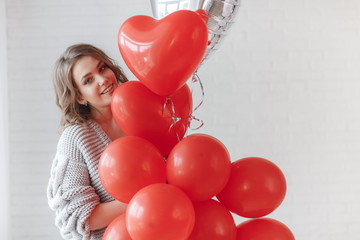 Valentine Beauty girl with colorful air balloons laughing, isolated on background. Beautiful Happy Young woman. holiday party. Joyful model having fun, playing and celebrating with red color balloon