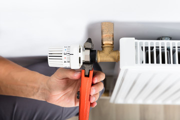 Male Plumber Fixing Thermostat Using Wrench