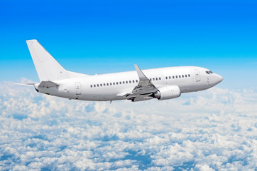 Fototapeta premium Passenger plane flies on a train above clouds and blue sky.