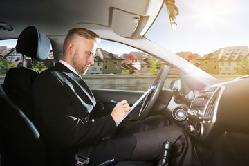 Man Writing On Clipboard Inside Self Driving Car