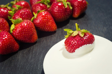 strawberries with cream on stone background, delicious first class organic fruit as a concept of summer vitamins