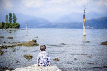 child sitting on a rock looking at Lake Maggiore