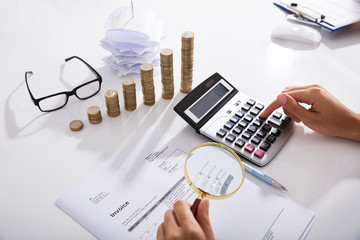 Businessperson Analyzing Bills With Magnifying Glass