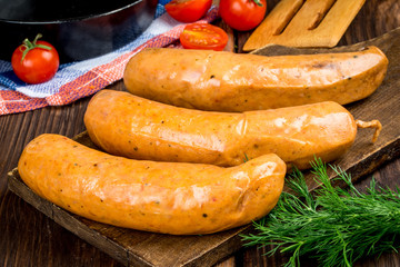 Smoked sausages are removed on a wooden background