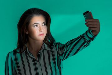 Young Woman Selfie with Light Beam on a Teal Background