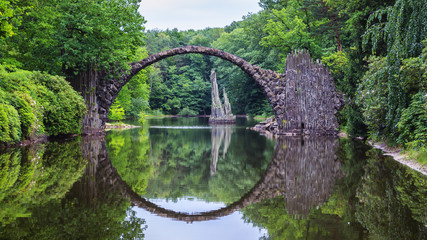 Rakotzbrücke (Rakotzbrucke) auch bekannt als Teufelsbrücke in Kromlau, Deutschland. Die Spiegelung der Brücke im Wasser erzeugt einen vollen Kreis.