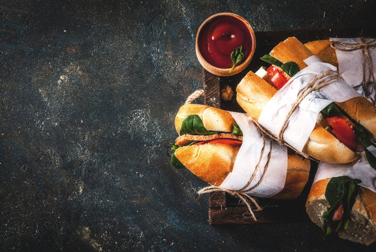 Fresh baguette sandwich with bacon, cheese, tomatoes and spinach, dark blue background copy space top view