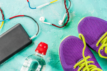Sports, fitness concept. Running sneakers, water bottle, headphones, dumbbells, smartphone, on a light blue background top view copy space