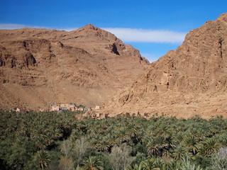 Fototapeta premium Old town of Tinghir, green palm oasis and rocky Atlas Mountains range landscape in southeastern Morocco
