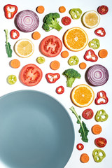 Creative layout of sliced vegetables and fruits with plate on white background.  Flat lay. Food vegan concept.