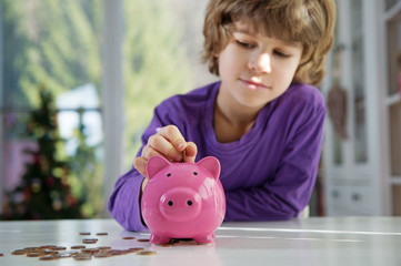 Little boy putting coins into piggy bank. Learning financial responsibility and projecting savings.