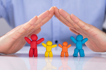 Hand Protecting The Colorful Family Made Up Of Clay
