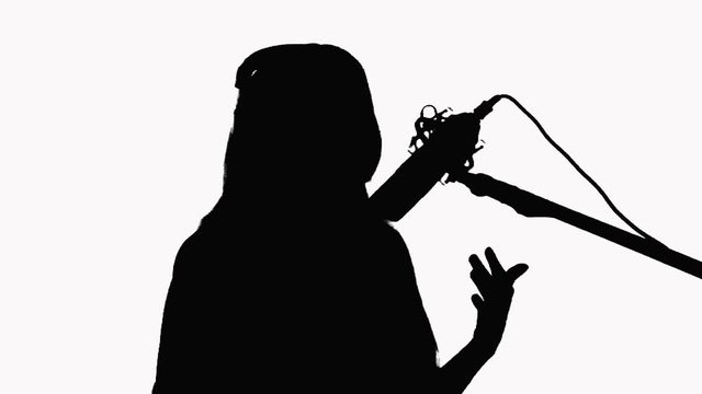 Silhouette of a young girl who sings in a studio microphone. Close-up On a white background.