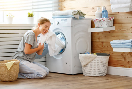 Happy housewife woman in laundry room with washing machine