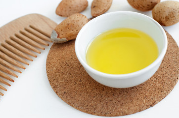 Small bowl with almond oil and wooden hair comb for natural hair care.