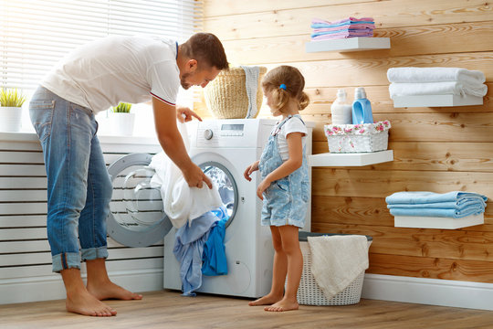 Happy family man father householder and child   in laundry with washing machine