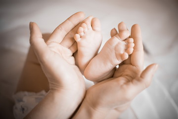 Small legs of the baby in the hands of the mother. Mother's love. little baby feet in mom's hands.
