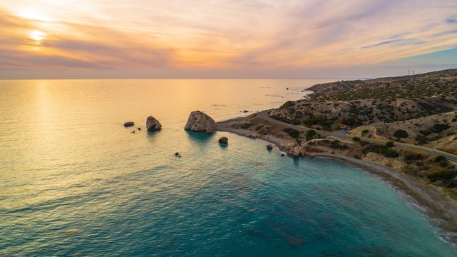     Aerial Bird's eye view of Petra tou Romiou, aka Aphrodite's rock a famous tourist travel destination landmark in Paphos, Cyprus. The sea bay of goddess Afroditi birthplace at sunset from above. 