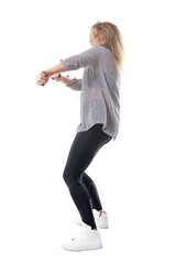 Energetic ecstatic blonde woman dancing. Side view. Full body length portrait isolated on white studio background. 