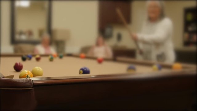 Shot of a women playing pool in a retirement home