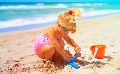 cute little girl play with sand on beach