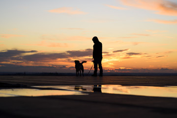 Silhouette of man with his dog at sunset on background